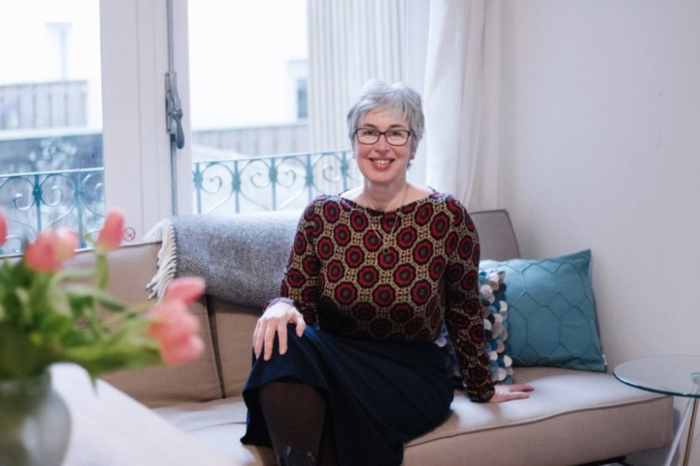 Porträit Birgit Arnold Inhaberin mygreenbnb, sitzend auf dem Sofa vor Fenestern