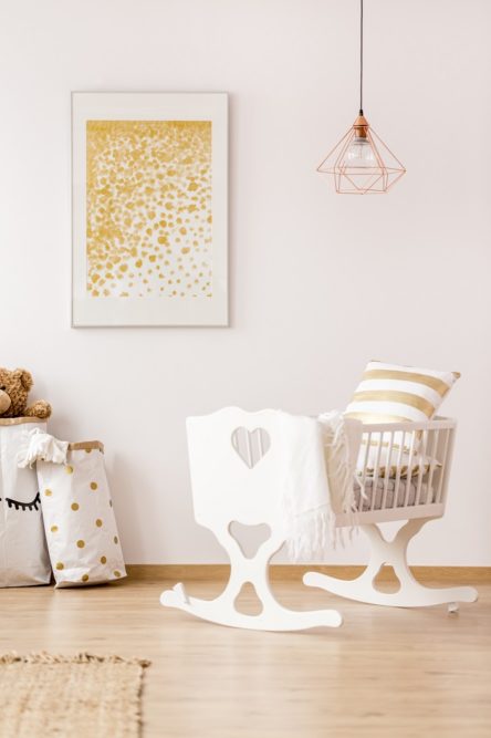 Babybett in einer Ferienwohnung im Kinderzimmer mit Bild, Lampe und Wäschesack